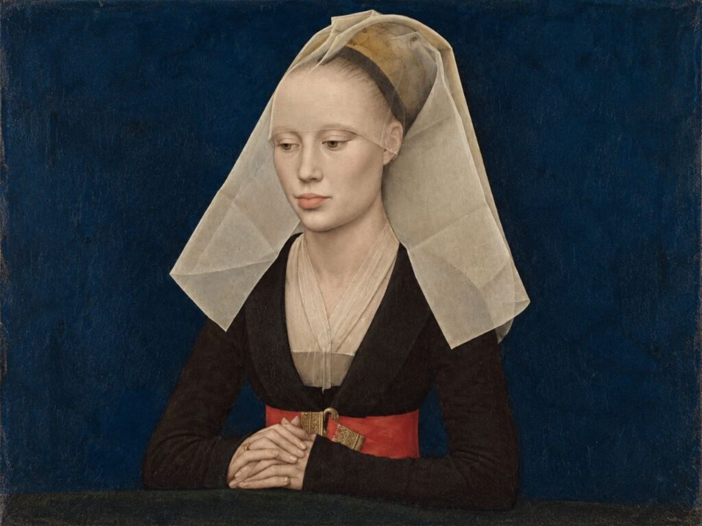 Renaissance portrait painting of a young woman with downcast eyes and folded hands wearing a black dress with a wide red belt and ornate gold buckle. A sheer white veil drapes over her head and shoulders against a deep blue background.