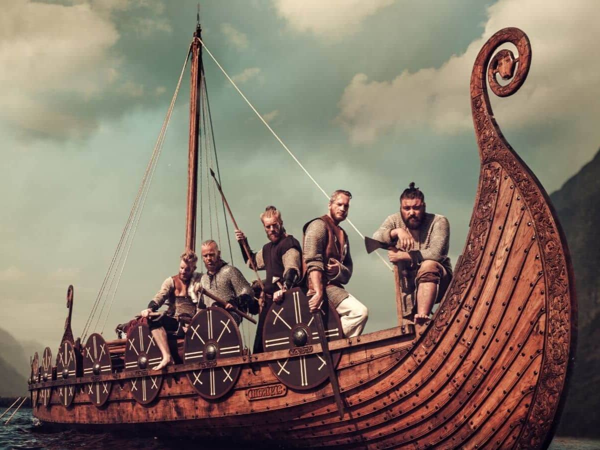 A group of Viking warriors in chainmail aboard a detailed wooden longship, ready for battle with shields and weapons, capturing the spirit of Norse seafaring in the era of "Did the Vikings Really Sail to America."