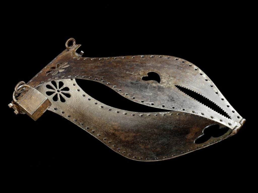 Close-up of a steel chastity belt with heart and floral cutouts, along with a serrated opening, highlighting the brutal design once linked to female chastity enforcement in medieval Europe.