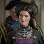 A stern-looking noblewoman in a Tudor headdress and rich gown from a dramatized historical scene, possibly representing Margaret Beaufort's determined political presence at court.