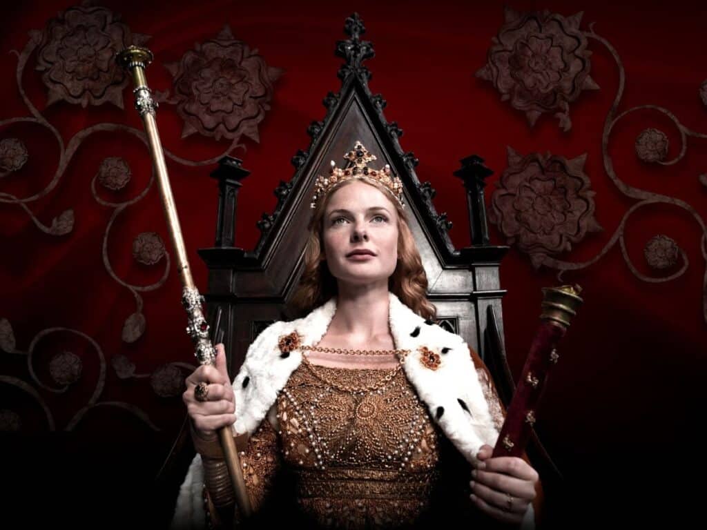 Regal depiction of Elizabeth Woodville on a throne, wearing a gold gown, fur-trimmed robe, and crown, holding the royal sceptre and orb against a red backdrop with white roses, symbolizing the House of York.