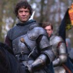 A cinematic portrayal of a brooding knight in steel armor on horseback, representing the Kingmaker, Richard Neville, with loyal soldiers and a heraldic flag behind him—capturing the ambition and tragedy of his political maneuvers.