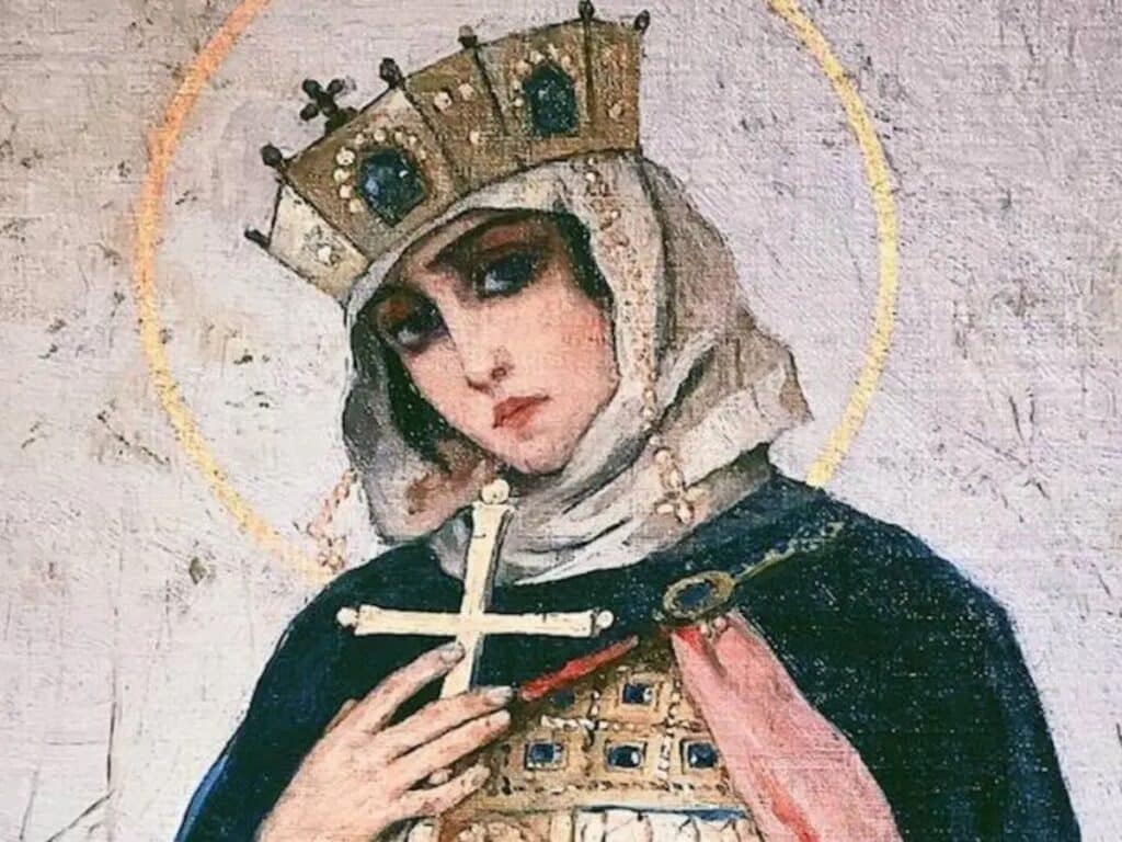 Painting of Olga of Kiev shown with a solemn expression, wearing a jeweled crown and veil, with a golden halo behind her head. She holds a cross to her chest, symbolizing her Christian faith and sainthood, and wears ornate robes with intricate blue and gold detailing.
