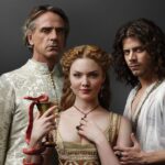 Promotional image from the TV series The Borgias featuring three characters: a stern older man, a young woman in gold holding a goblet entwined with a red snake, and a brooding young man. The central figure represents Lucrezia Borgia.