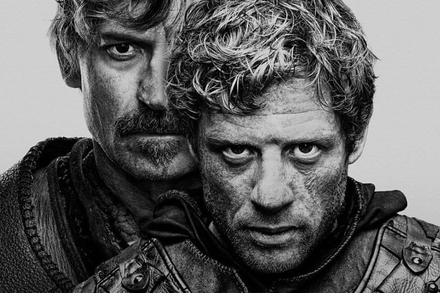 Black-and-white portrait of two intense, battle-worn men—one standing closely behind the other—staring forward with determination. Character-driven promo for BBC One’s new historical drama, King & Conqueror.
