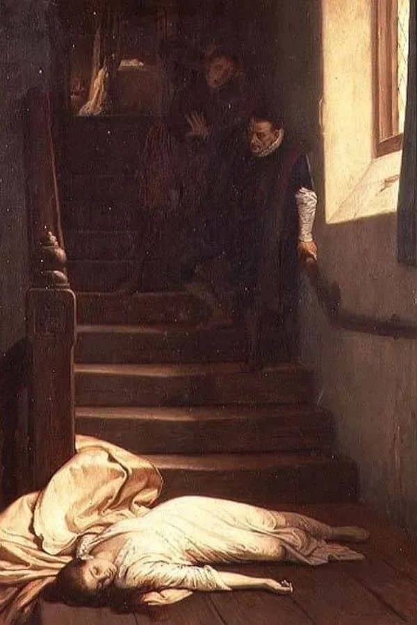 Close-up of Amy Dudley's body at the base of a staircase, her head tilted to one side and her white dress pooling around her in soft folds. This image emphasizes the tragedy and enigma surrounding Amy Dudley's sudden death.
