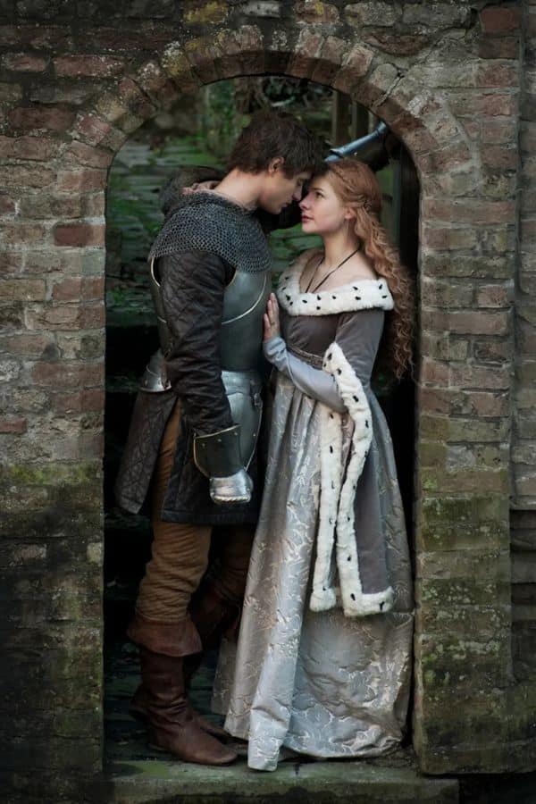 A medieval knight and a noblewoman stand closely beneath a stone archway, sharing an intense, intimate gaze. This romantic moment echoes the intrigue behind the question was Elizabeth Woodville a witch, as her beauty and mysterious influence stirred suspicion in her time.