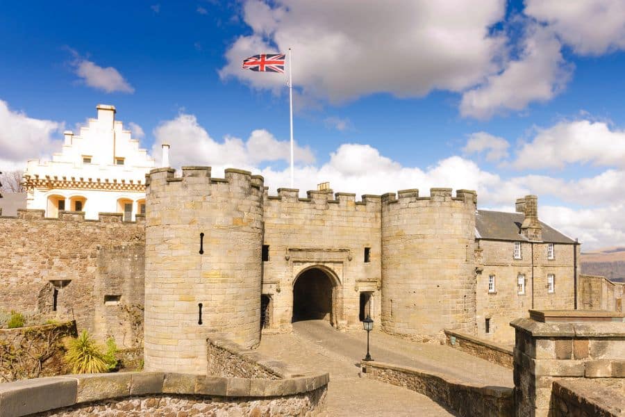 The fortified entrance of Stirling Castle in Scotland, with stone towers and the Union Jack flag flying above, highlights its role as a royal stronghold.