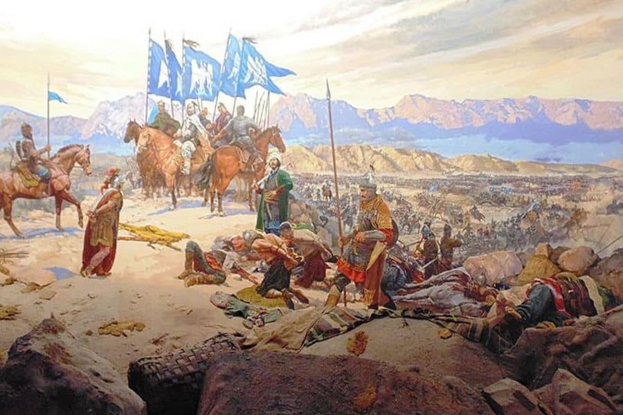 Painting of the aftermath of a historic medieval battle showing wounded soldiers and medics on rocky terrain, with mounted commanders under blue flags overlooking a vast battlefield against a mountain range.