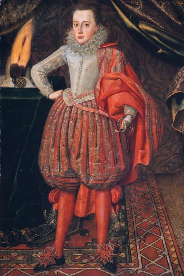 Full-length portrait of a young noble boy in lavish red and silver Elizabethan attire with a sword at his waist. This is believed to be a youthful depiction of George Villiers, showcasing his aristocratic origins and early nobility.