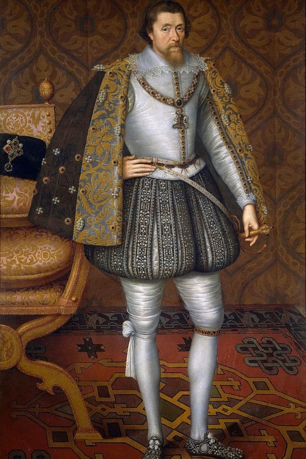 Portrait of King James I wearing ornate Renaissance attire with a richly embroidered cloak and ruffled collar, standing beside a carved throne. Robert Carr served as a close advisor and favorite to King James I during this time.