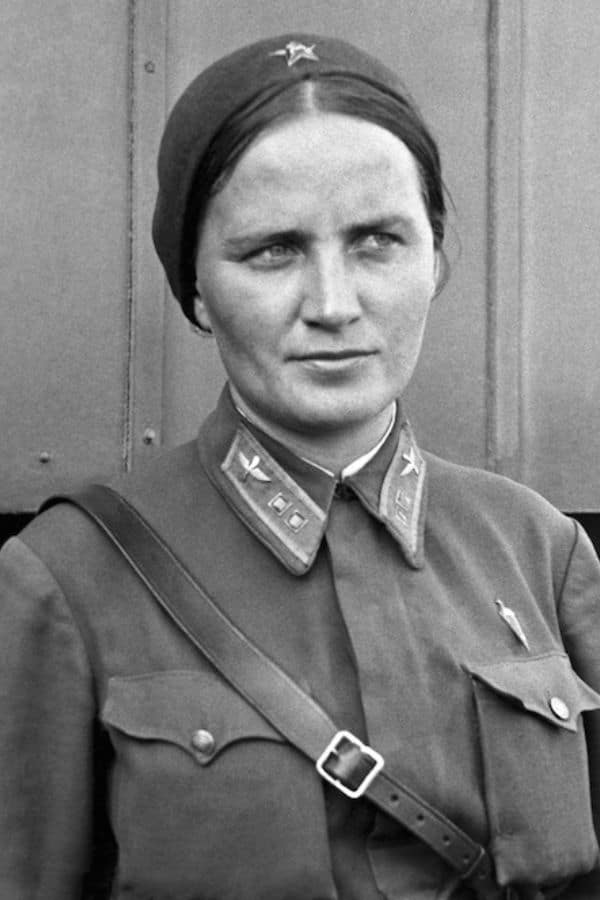 Close-up portrait of a stern-looking Soviet officer in a uniform with pilot insignia on her collar. She was one of the Night Witches, known for flying daring night bombing missions during WWII.