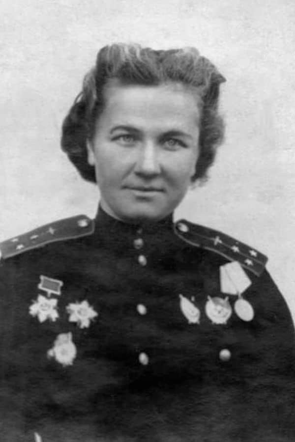 A formal portrait of a Soviet woman officer with numerous medals on her chest, symbolizing her bravery as a member of the Night Witches aviation regiment. Her uniform reflects her high rank and service distinction.