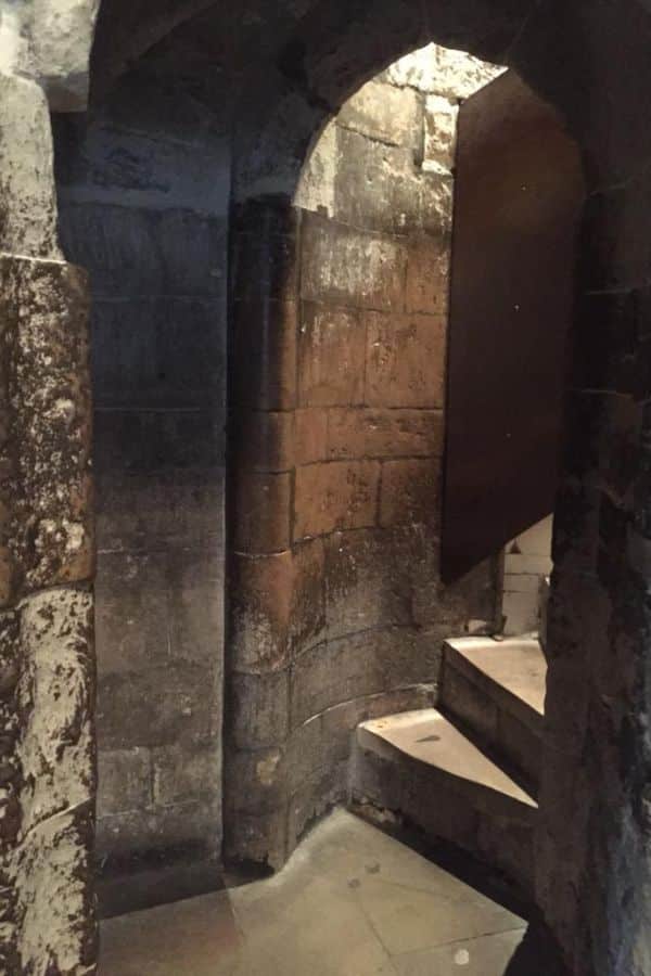 Narrow stone spiral staircase inside the Tower of London, with worn steps and arched walls, representing one of the hidden, shadowy passageways where the Princes in the Tower may have been held or moved.