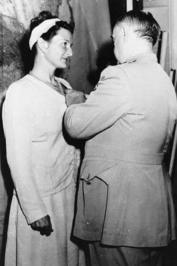 Black and white photo of Virginia Hall receiving a military decoration, recognizing her bravery and intelligence work during World War II.