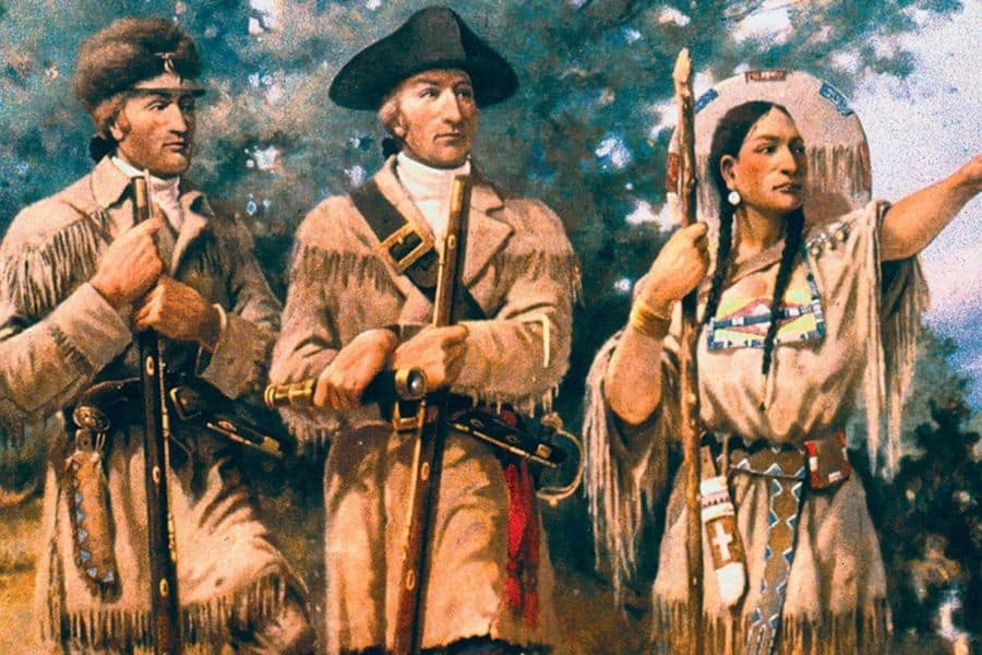 Historical painting of two explorers standing beside a Native woman who points toward the distance. The scene connects Sacagawea with the Lewis and Clark expedition and westward travel.