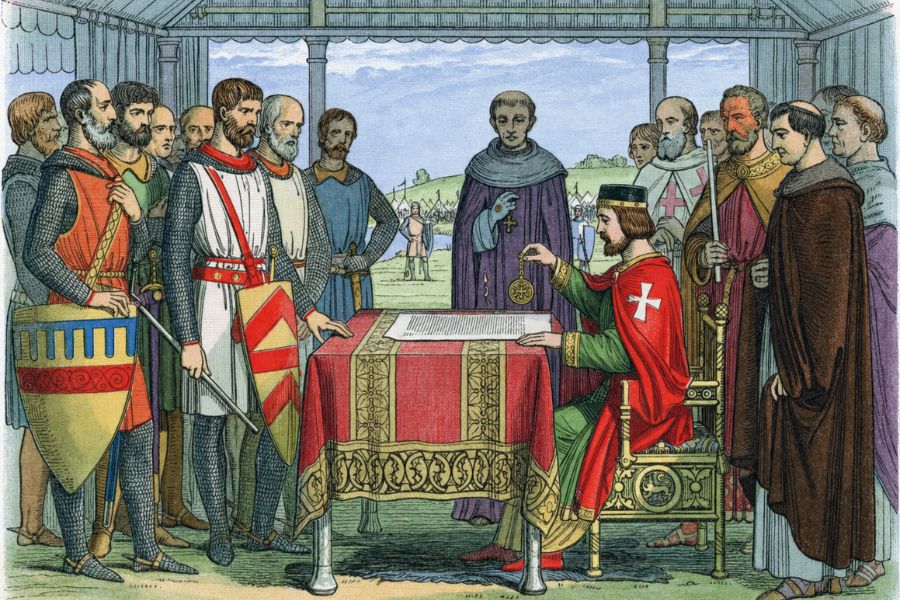 Historical illustration of King John seated before English barons and church leaders as he grants the Magna Carta. A document rests on a covered table while armed knights and clergy gather around him.