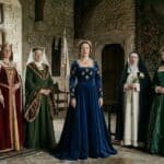 Five women in medieval dresses stood in a castle