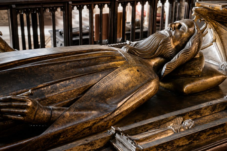 Bronze tomb effigy of Edward III resting inside a medieval church with hands folded and head supported on a cushion. The detailed monument commemorates Edward III and reflects the craftsmanship of royal funerary art from the period.