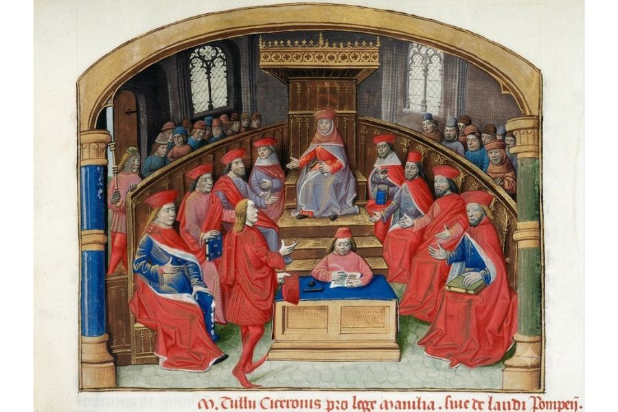 Medieval court scene showing red robed clerics and officials gathered around a seated judge in an arched chamber. A clerk writes at a blue covered desk while a speaker addresses the court. A cropped line of Latin text appears below the scene but is not fully legible.