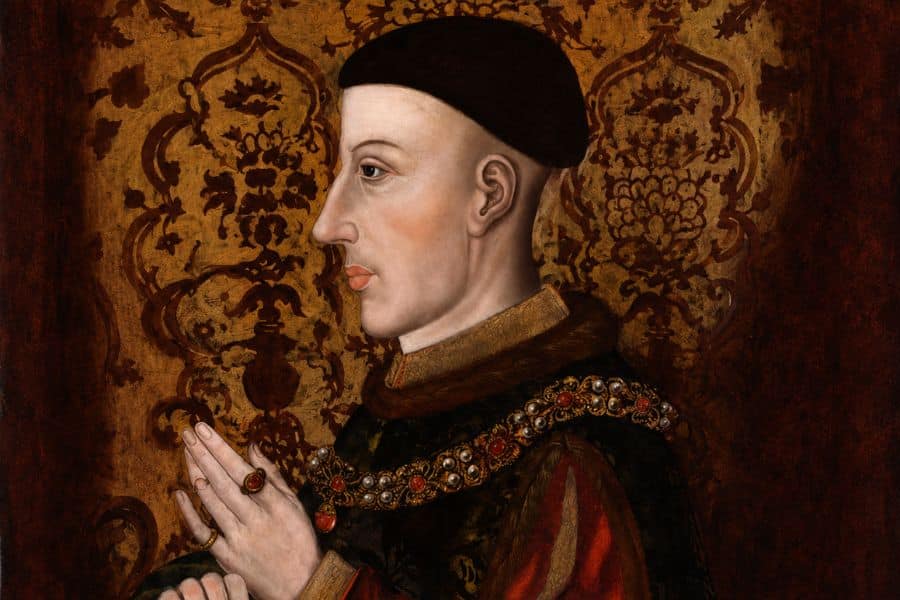 Side profile portrait of King Henry V wearing a black cap, richly decorated robes and jeweled collar against an ornate patterned background. The painting represents the English king who married Catherine of Valois.