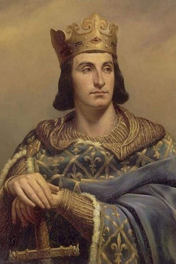 A crowned medieval king wears a blue robe patterned with gold fleur de lis and a heavy fur trimmed mantle. His hands rest on the hilt of a sword to emphasize his royal and military authority.