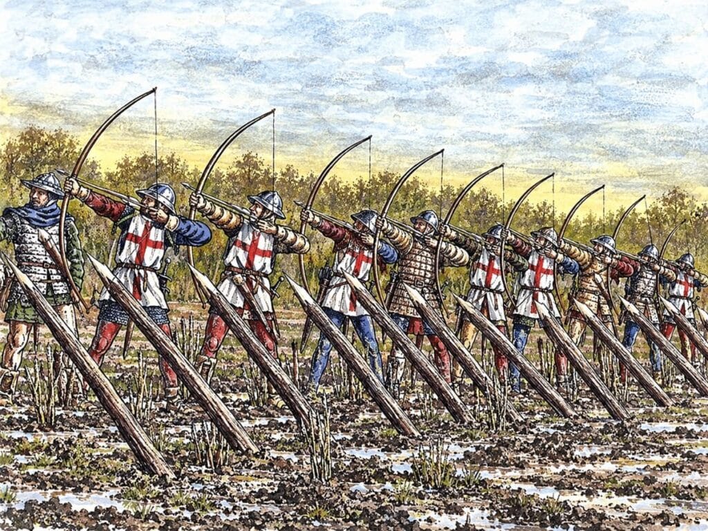 Medieval English archers stand behind sharpened wooden stakes with longbows drawn across a muddy battlefield. The defensive formation illustrates the role of English longbowmen at the Battle of Agincourt.